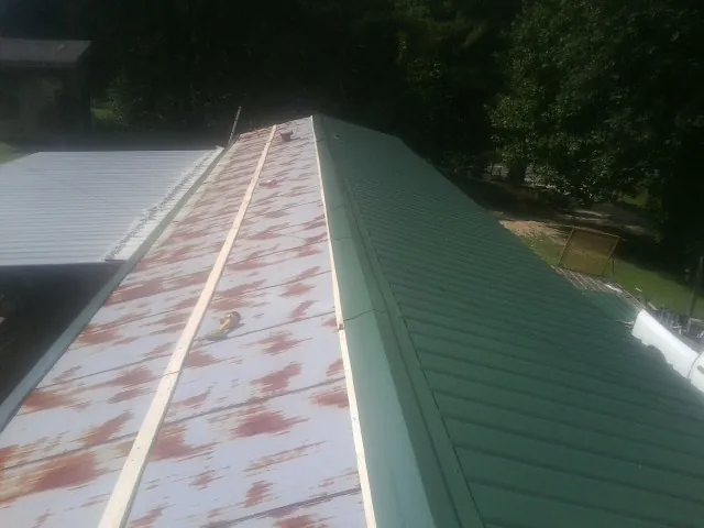 Old rusted panels beside newly installed green metal roofing — Wind Damage Roof Repair by Roofing Brothers in Prosper