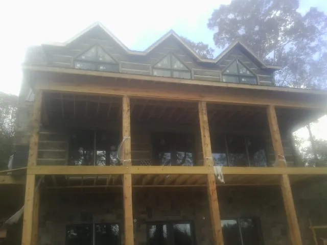 Dormers and porch framing on a large log home under construction — Roof Coating work by our crew in Prosper