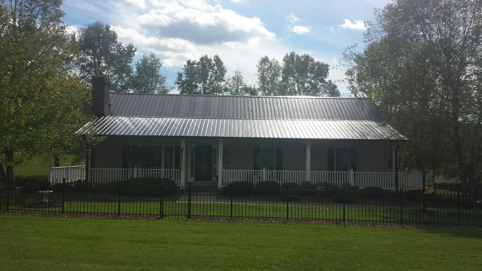 Gray metal roof on a brick ranch with a full width front porch — Gutter Guard Installation work by our crew in Prosper
