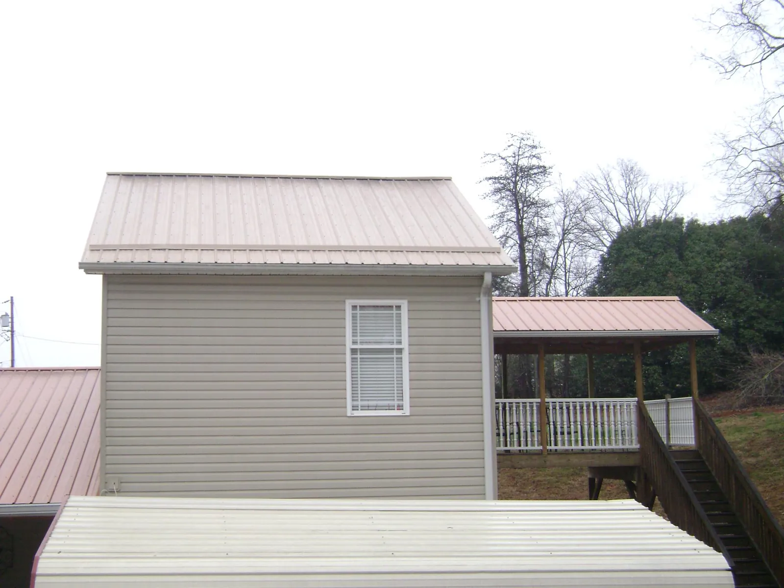 Tan metal roofs on a two story addition and attached porch, from a Roof Replacement job in Prosper